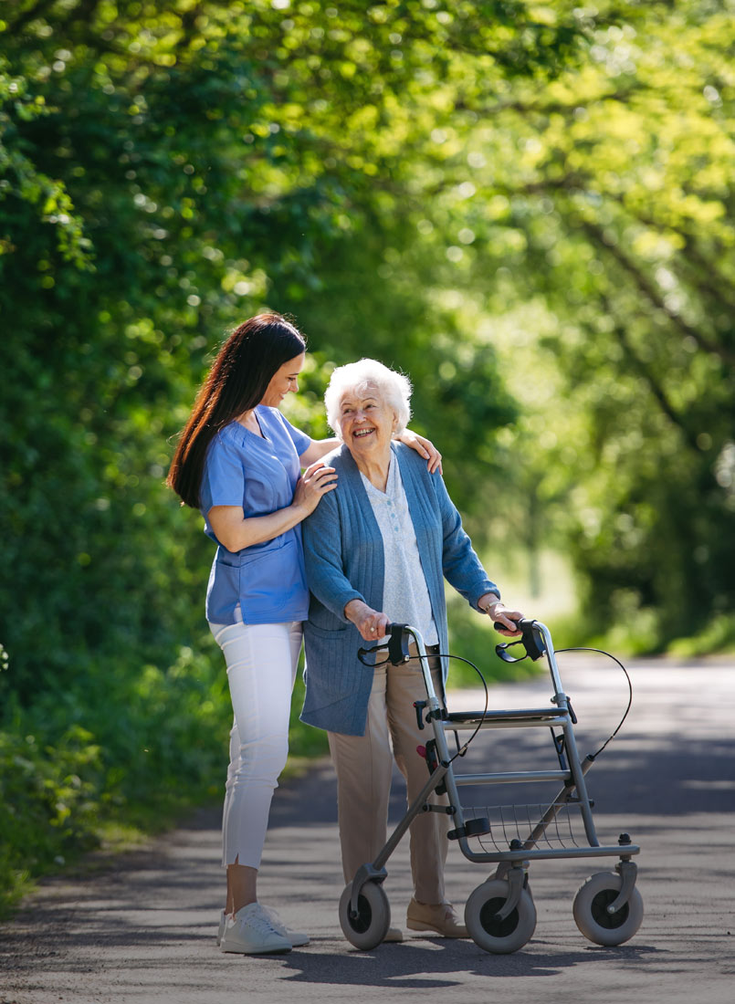 Pflegerin geht mit altter Dame und Rollator spazieren im Seniorenheim St.Vinzenz
